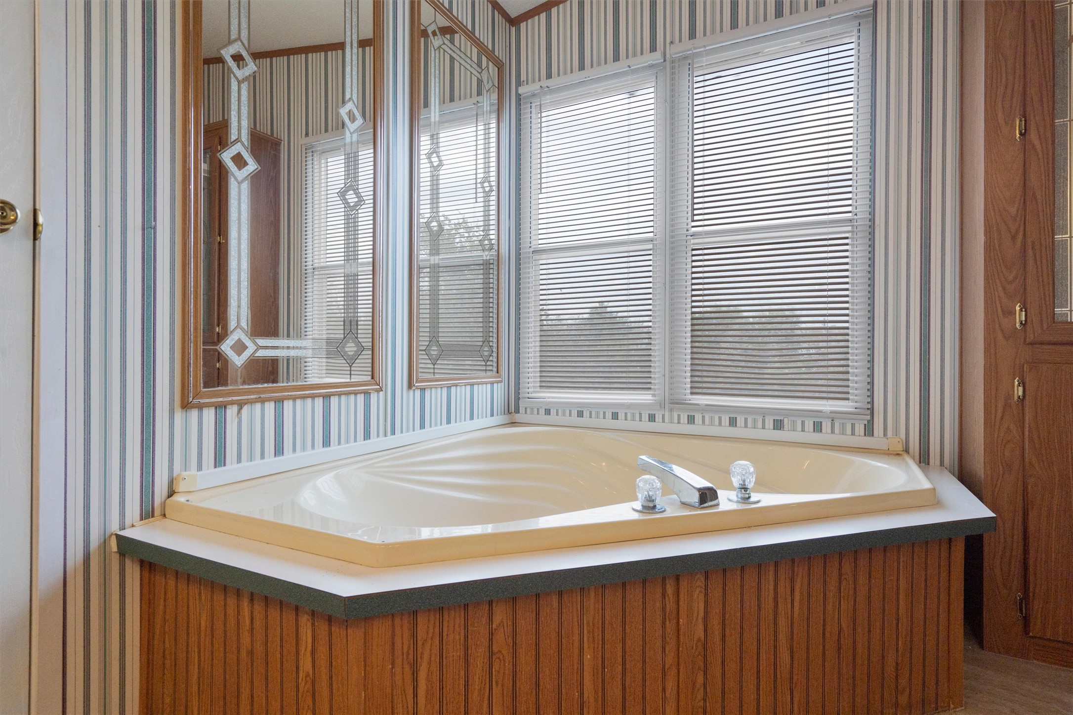 3075 Old Black Colony Road, Unit D Buda, TX 78610 - Photo 14 of 26 A corner soaking tub rests beneath large windows paired with wood paneling details.