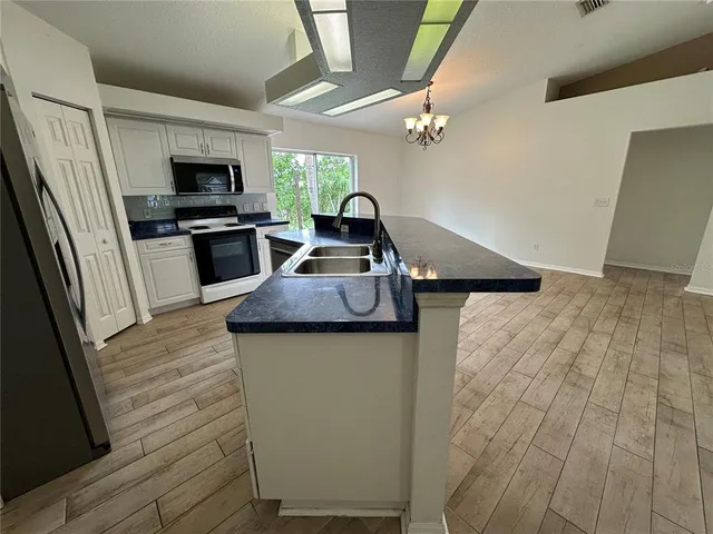 a view of a kitchen with kitchen island a sink wooden floor and a large window