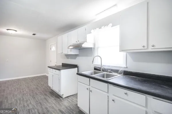 a kitchen with granite countertop a sink a stove and cabinets