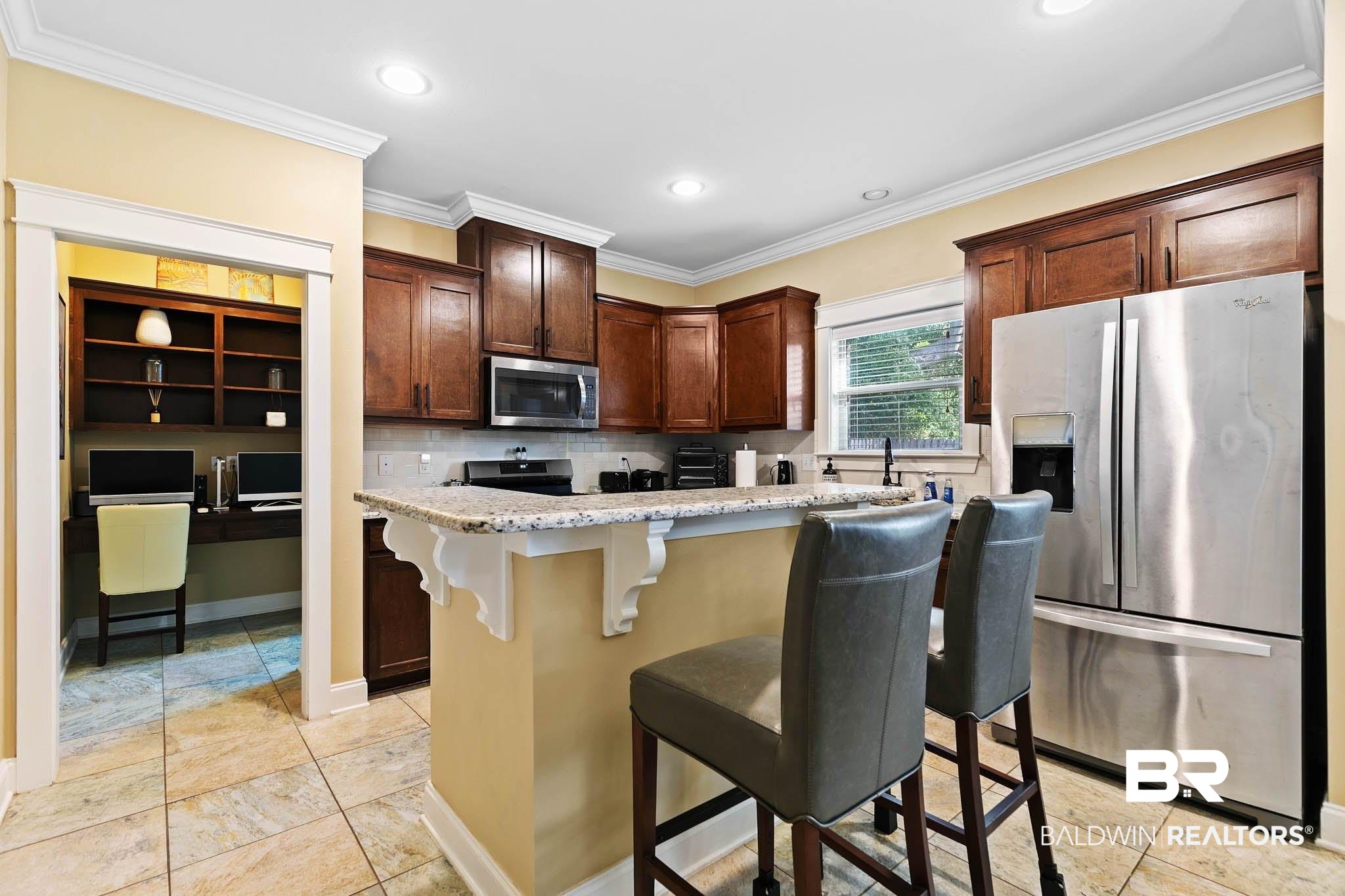 19740 Bunker Loop Fairhope, AL 36532 - Photo 11 of 33 Kitchen featuring stainless steel appliances, ornamental molding, a center island, a kitchen breakfast bar, and light stone countertops
