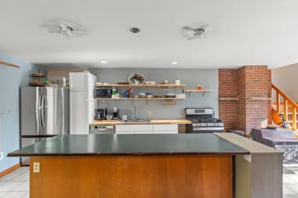 a room with kitchen island a sink a stove and a refrigerator with wooden floor