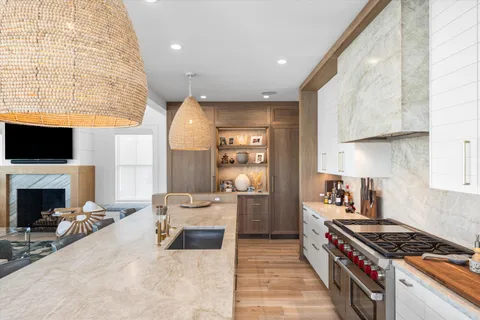 a kitchen with stainless steel appliances a stove a sink dishwasher and a fireplace with wooden floor