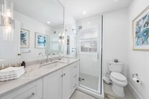 a bathroom with a granite countertop sink a toilet and a shower
