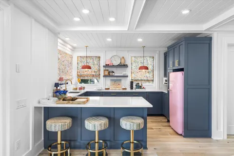 a kitchen with stainless steel appliances granite countertop a refrigerator and chairs