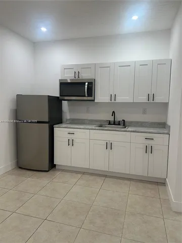 a kitchen with a sink a stove a refrigerator and white cabinets