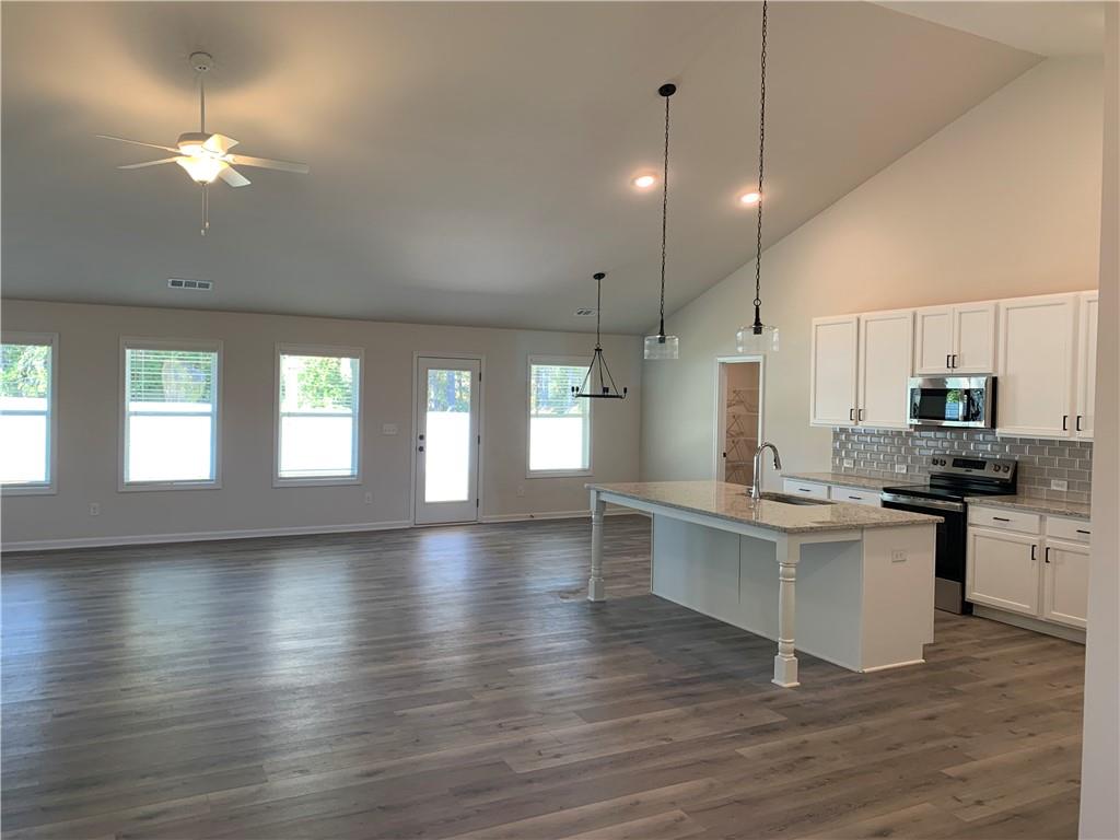 755 Rodeo Drive Auburn, GA 30011 - Photo 4 of 15 a kitchen with stainless steel appliances granite countertop a stove top oven a chimney cabinets and wooden floor