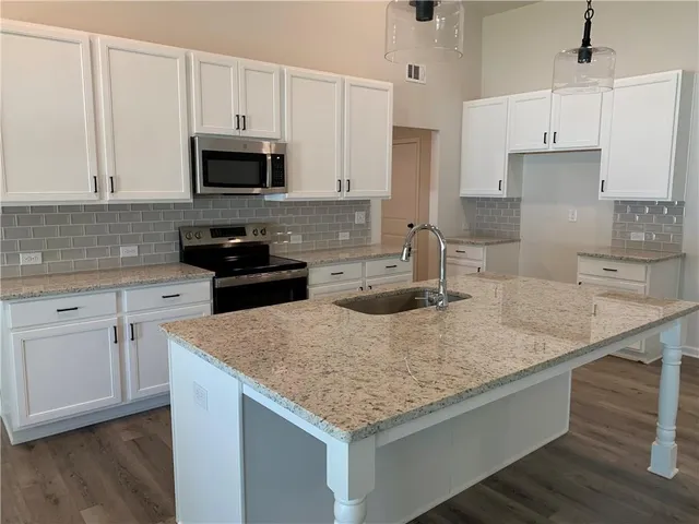 a kitchen with stainless steel appliances granite countertop a sink stove and white cabinets