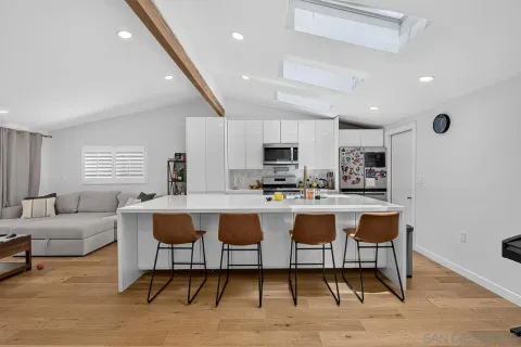 a living room with stainless steel appliances kitchen island granite countertop furniture and a wooden floor