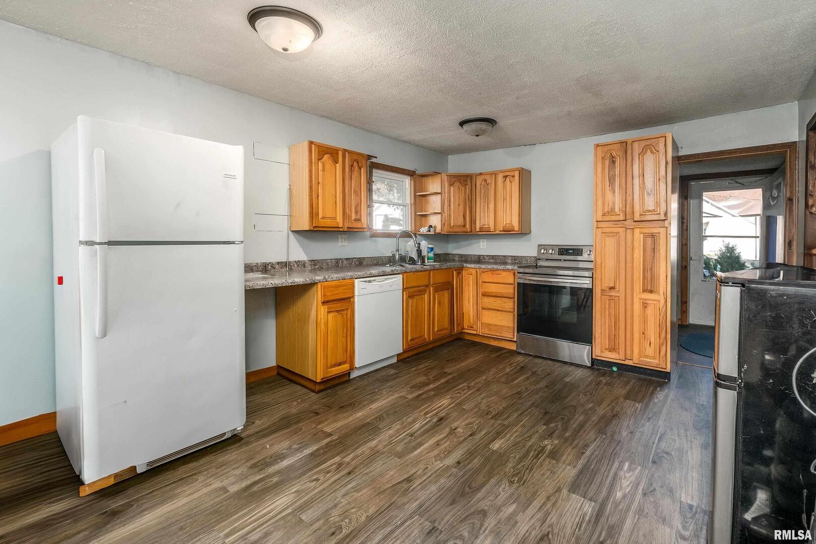 320 Franklin Avenue Orient, IL 62874 - Photo 5 of 26 a kitchen with stainless steel appliances granite countertop a refrigerator a sink dishwasher a stove top oven a refrigerator and cabinets with wooden floor