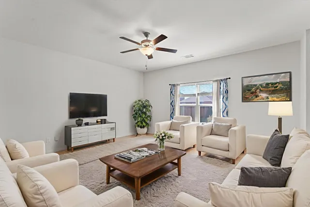 a living room with furniture a flat screen tv and a window