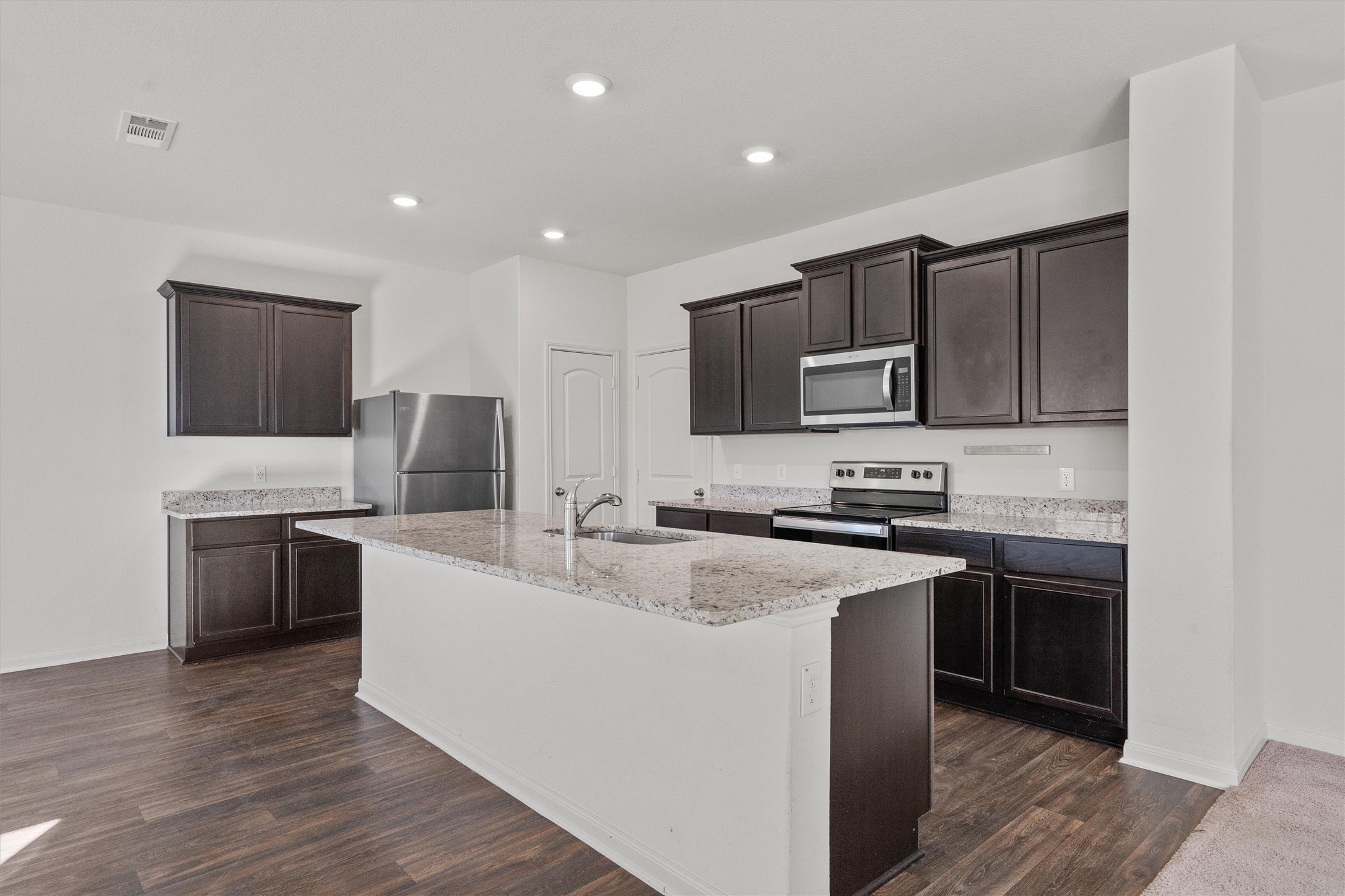 14405 Boomtown Way Elgin, TX 78621 - Photo 7 of 39 a kitchen with stainless steel appliances granite countertop a stove top oven a sink dishwasher a refrigerator and a microwave oven with wooden floor