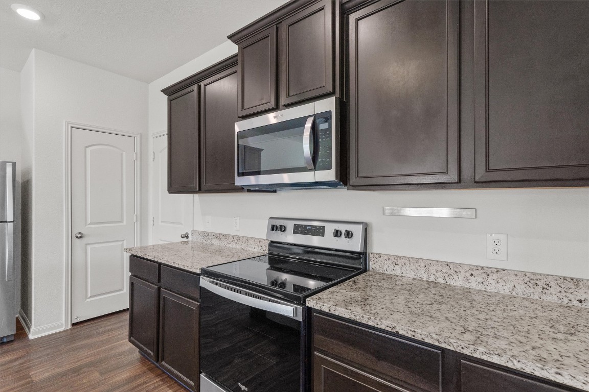 14405 Boomtown Way Elgin, TX 78621 - Photo 8 of 39 a kitchen with stainless steel appliances granite countertop a sink stove and microwave