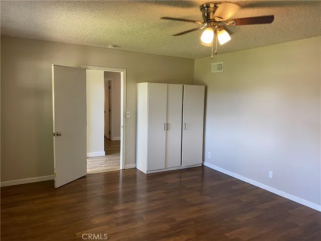 an empty room with wooden floor closet and windows