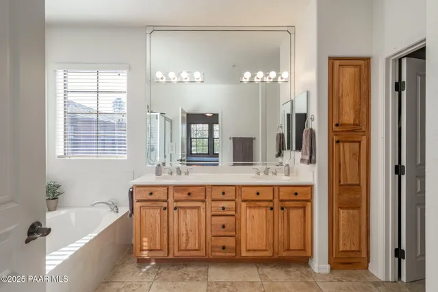 a spacious bathroom with a double vanity sink a large mirror a bathtub and shower