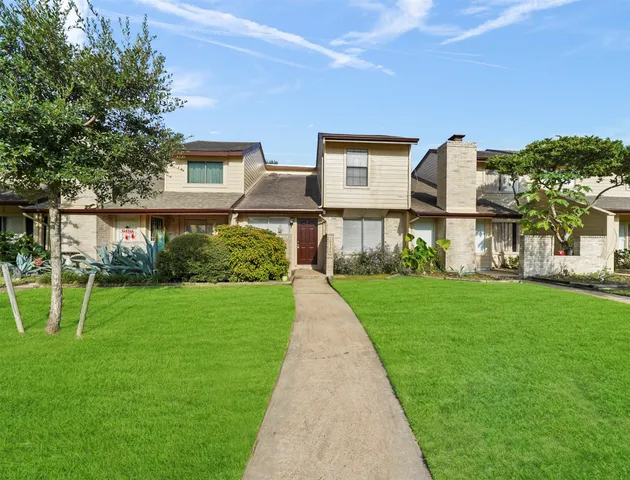 a front view of a house with a yard and potted plants