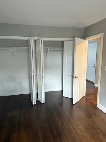 an empty room with wooden floor & closet area