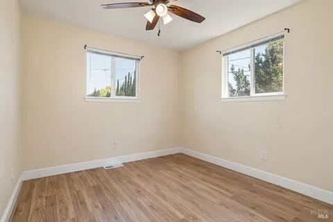 a view of empty room with wooden floor and fan
