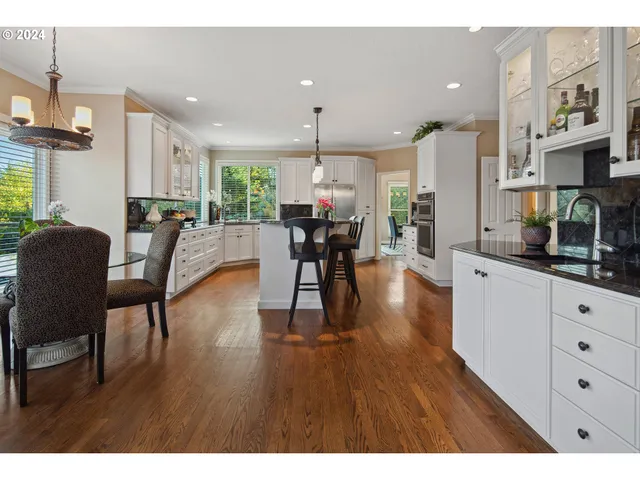 a kitchen with stainless steel appliances kitchen island granite countertop a stove a sink and white cabinets