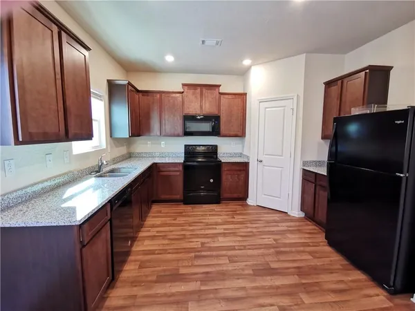 a large kitchen with stainless steel appliances granite countertop a refrigerator and a sink