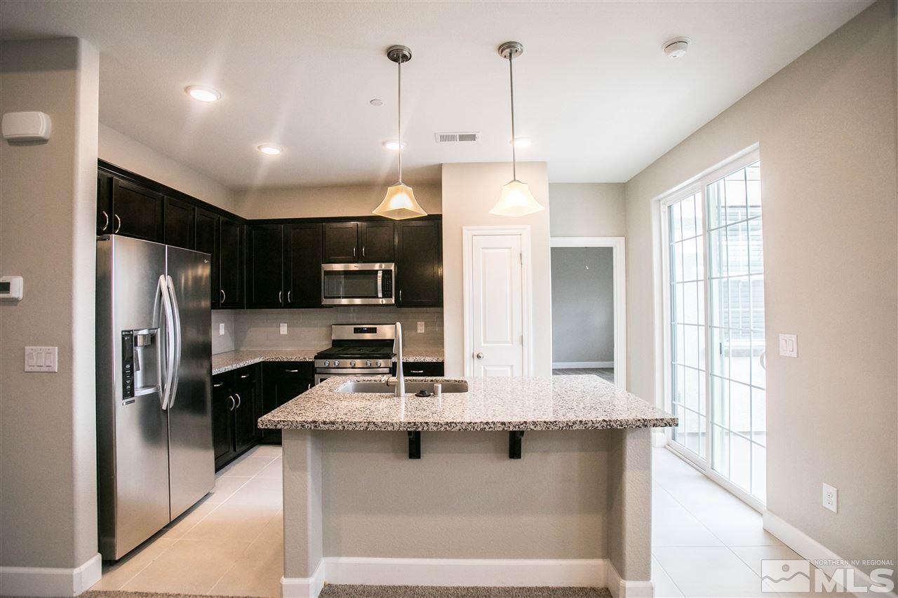 1856 Sea Horse Road, Unit A Reno, NV 89521 - Photo 4 of 16 a kitchen with stainless steel appliances kitchen island granite countertop a refrigerator a oven a sink with island and windows