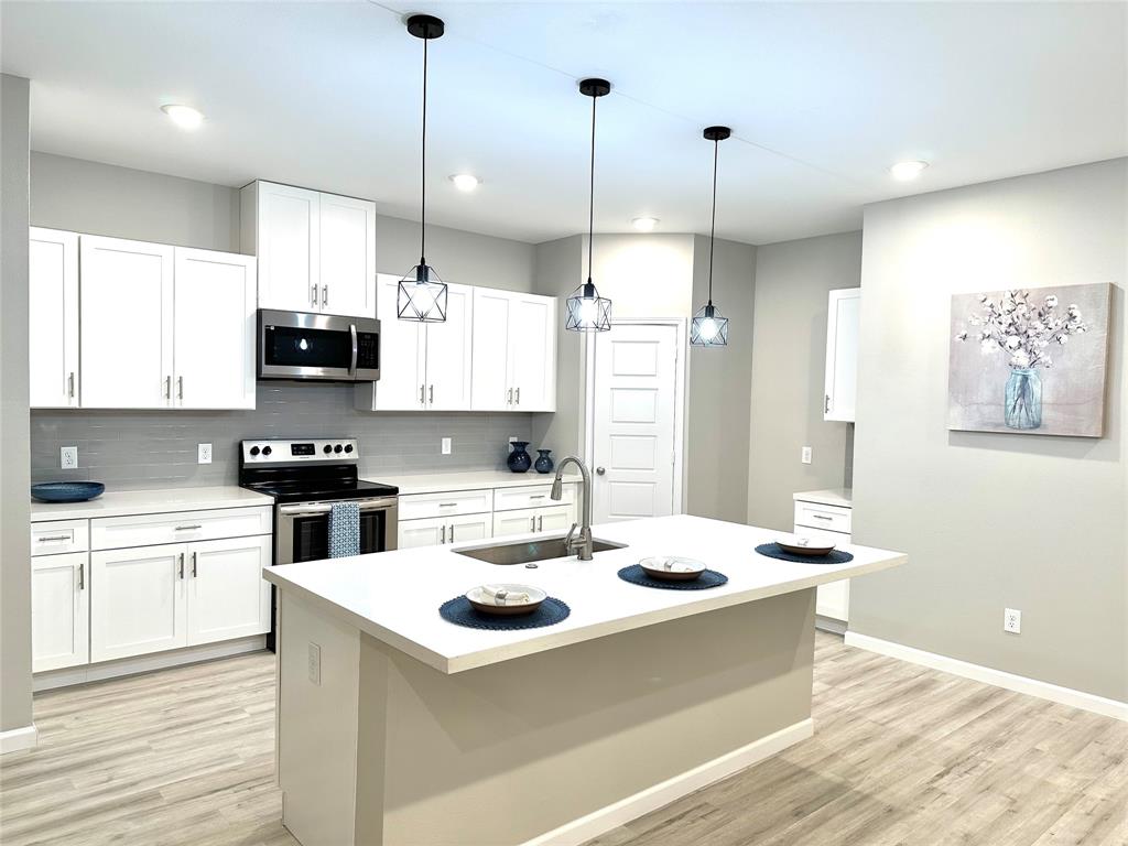 a kitchen with stainless steel appliances kitchen island a white counter space a sink and cabinets