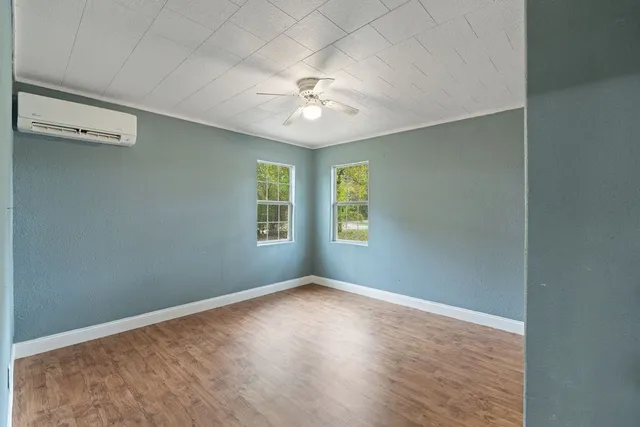 an empty room with wooden floor and windows