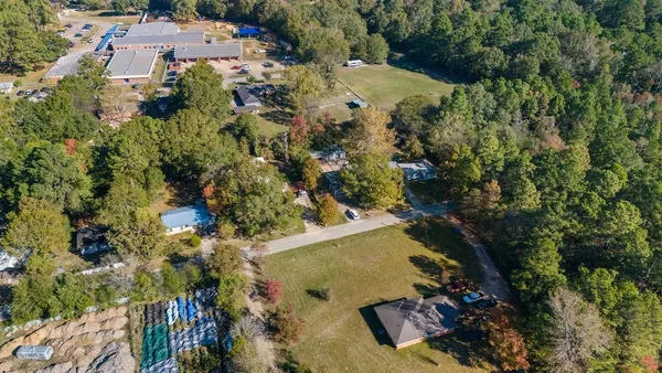 an aerial view of residential house with outdoor space and trees all around