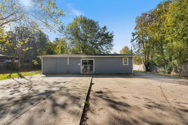 a backyard of a house with table and chairs under an umbrella