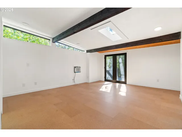 a view of an empty room with a window and kitchen view