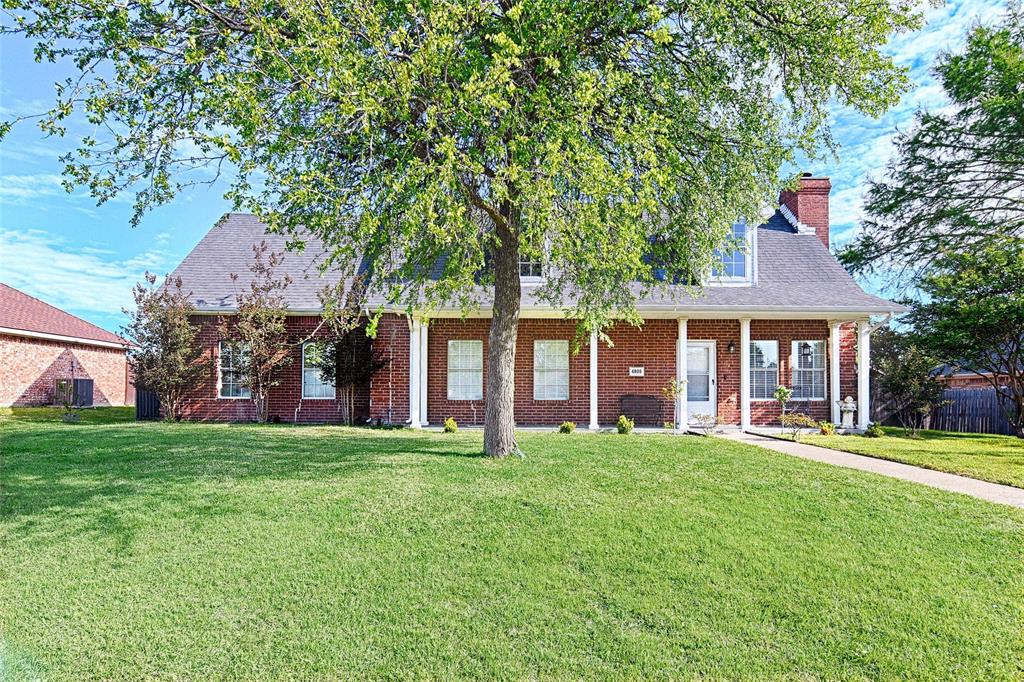 a front view of a house with a garden and trees