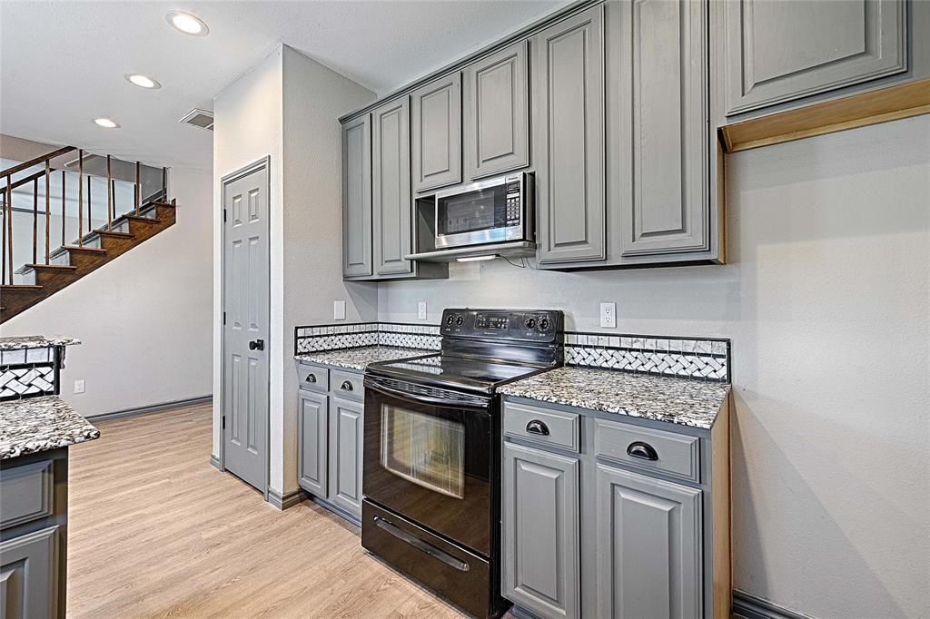 4805 Hunters Ridge Drive Sachse, TX 75048 - Photo 11 of 24 a kitchen with granite countertop cabinets stainless steel appliances and wooden floor