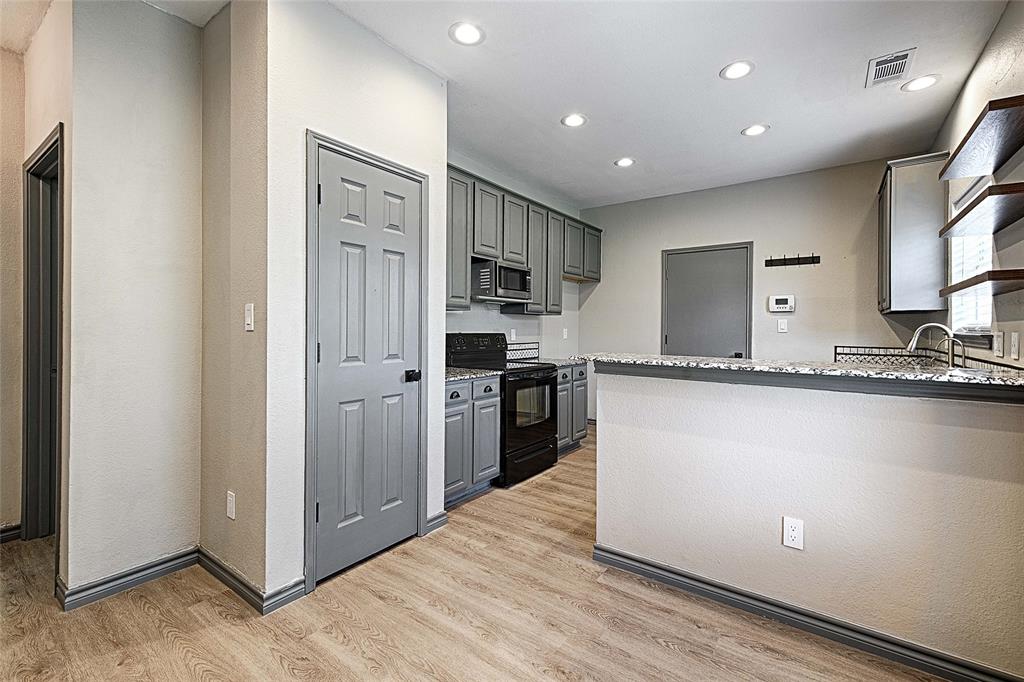 4805 Hunters Ridge Drive Sachse, TX 75048 - Photo 10 of 24 a kitchen with granite countertop a refrigerator and a stove top oven