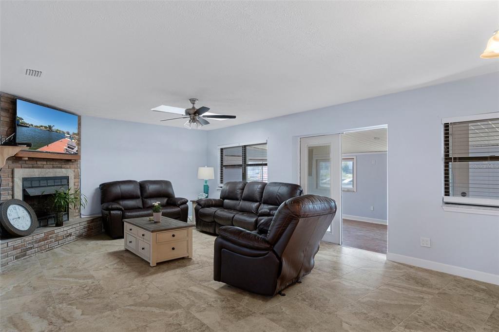 4964 Cedarbrook Lane Hernando Beach, FL 34607 - Photo 12 of 29 a living room with furniture a fireplace and a flat screen tv