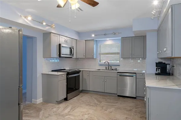 a kitchen with stainless steel appliances granite countertop a stove top oven a sink dishwasher a refrigerator and a microwave oven