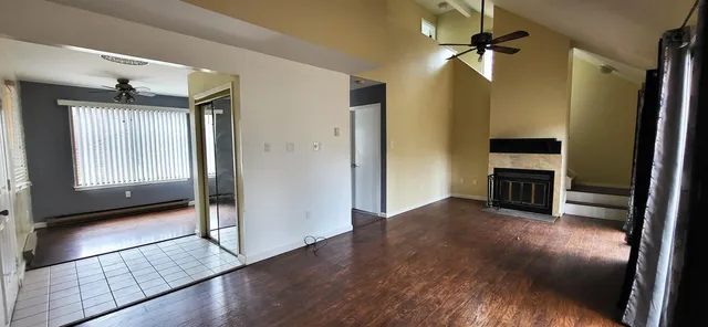 a view of a livingroom with a fireplace a ceiling fan and window