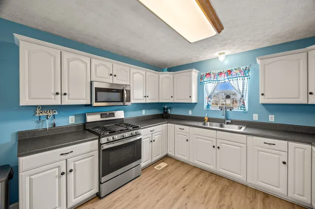 a kitchen with granite countertop white cabinets and white appliances
