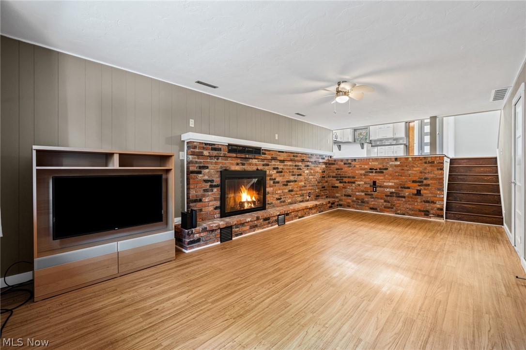 17583 Shurmer Road Strongsville, OH 44136 - Photo 19 of 50 Spacious living area featuring wood-finish flooring, a full brick fireplace with a white mantel, and paneled walls