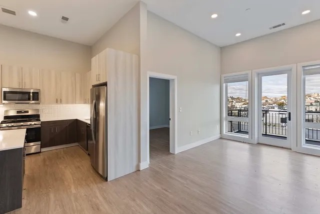 a kitchen with stainless steel appliances a refrigerator and wooden floor