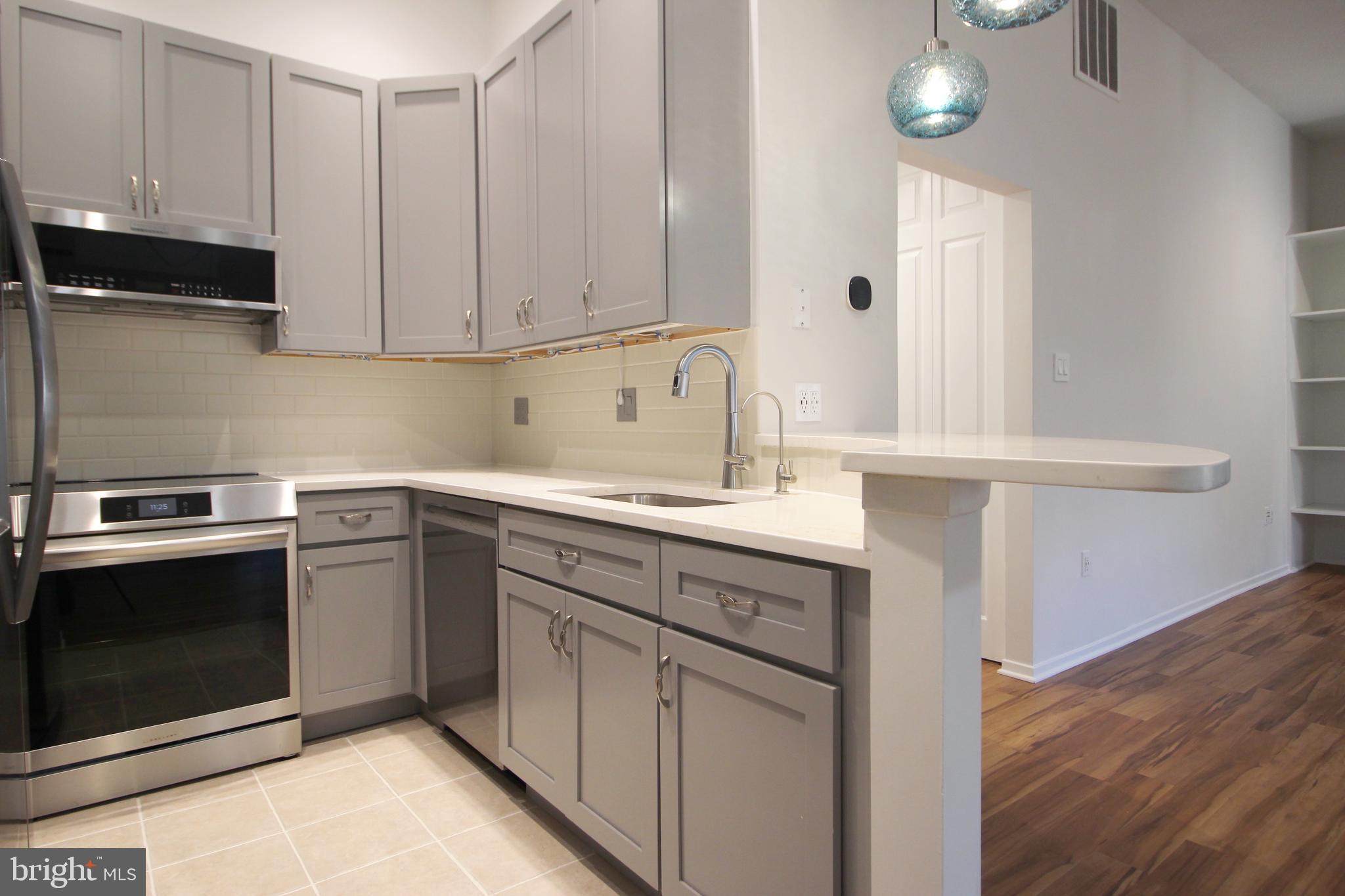1956A Villaridge Drive, Unit 1956B Reston, VA 20191 - Photo 14 of 24 a kitchen with granite countertop white cabinets sink and stainless steel appliances