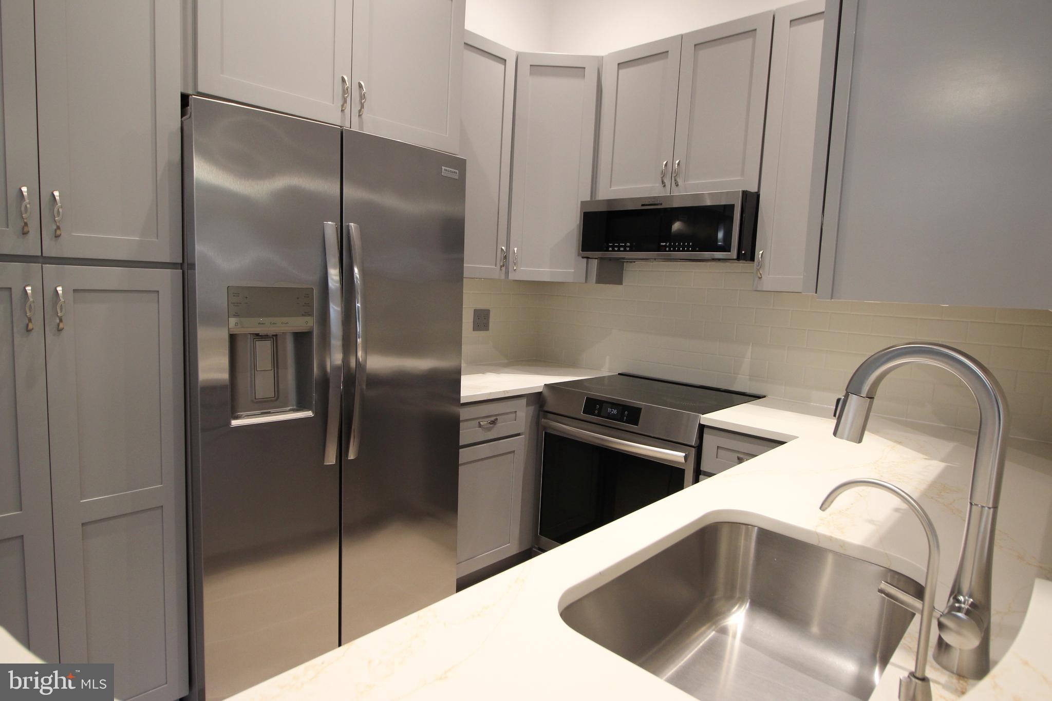 1956A Villaridge Drive, Unit 1956B Reston, VA 20191 - Photo 15 of 24 a kitchen with stainless steel appliances granite countertop a refrigerator a stove and a sink with wooden floor