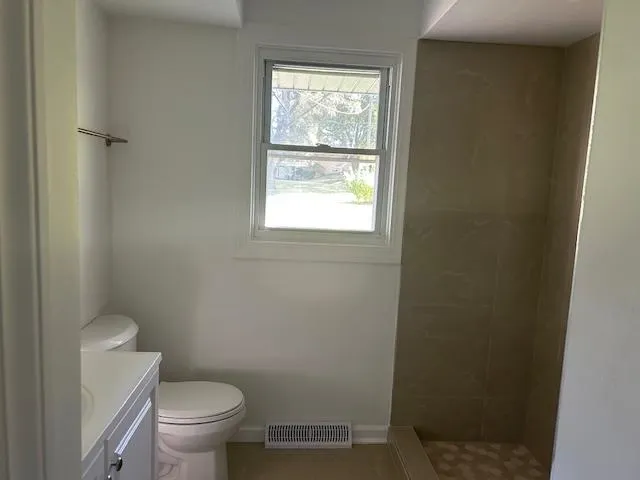 a white toilet sitting next to a window in a bathroom