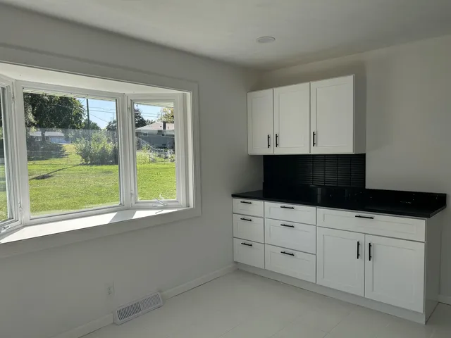 a kitchen with white cabinets and a window