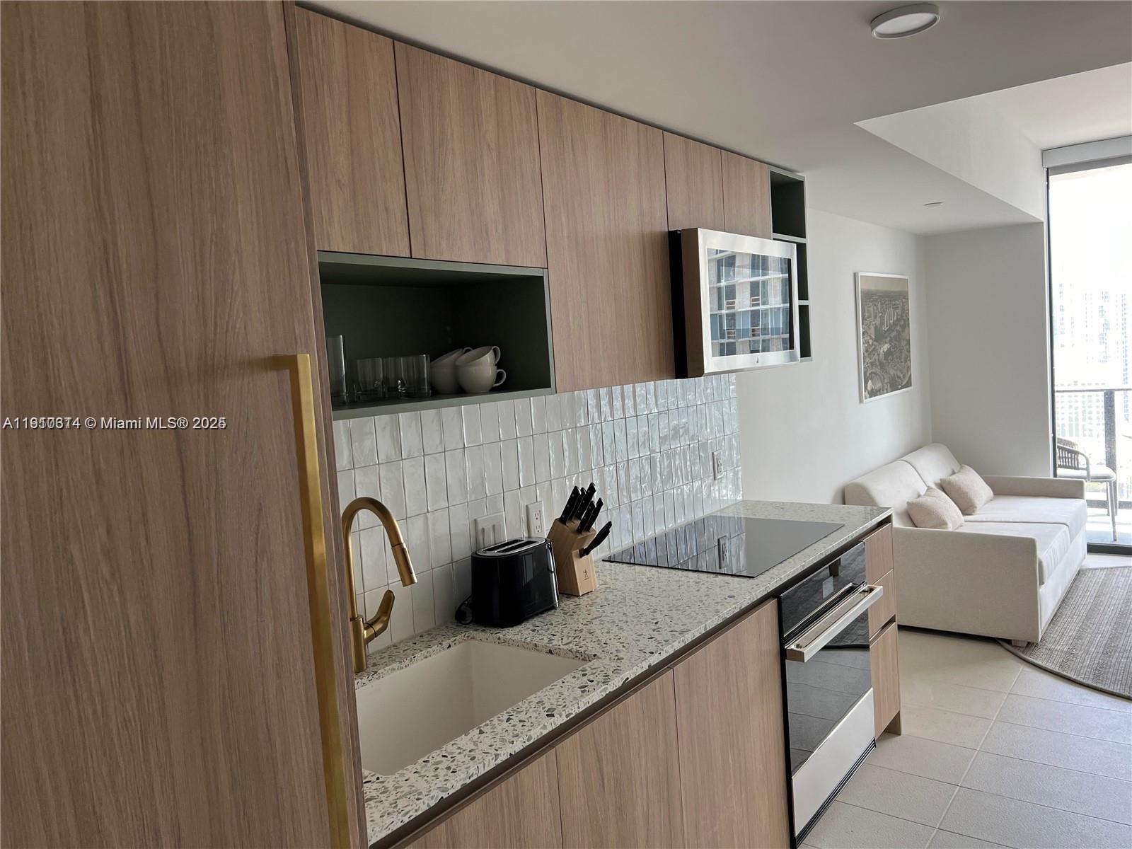 159 Northeast 6th Street, Unit 2807 Miami, FL 33132 - Photo 4 of 13 a kitchen with stainless steel appliances granite countertop a sink a microwave a refrigerator and white cabinets