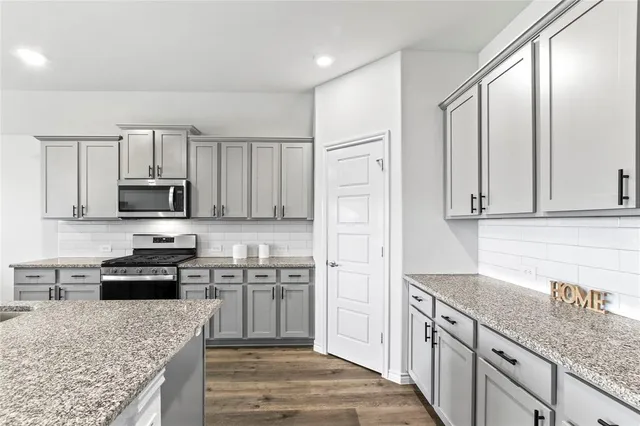 a kitchen with stainless steel appliances granite countertop a stove a sink and a microwave
