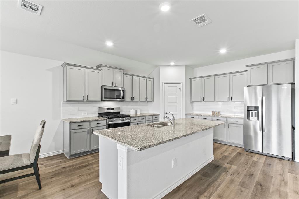 2920 Pinecrest Drive Aubrey, TX 76227 - Photo 8 of 27 a kitchen with a sink a stove a refrigerator and white cabinets