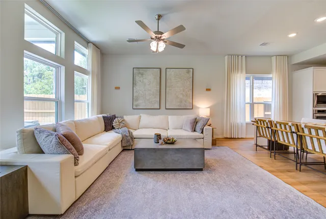 a living room with furniture a wooden floor and a large window