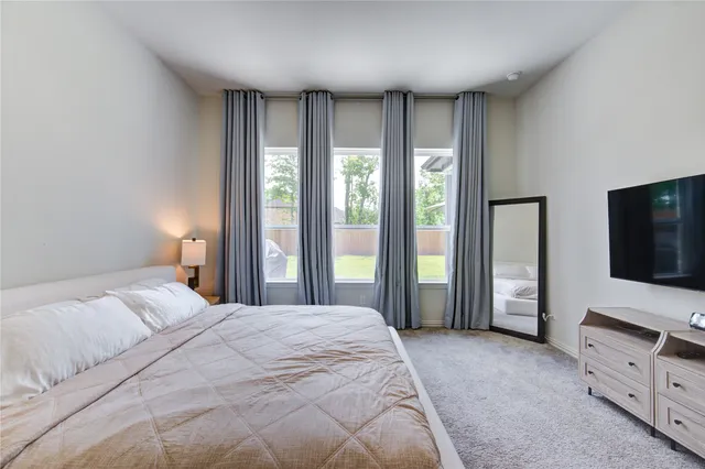 a bedroom with a bed flat screen tv and a large window