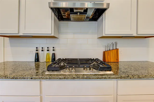a kitchen with granite countertop a sink a stove and cabinets