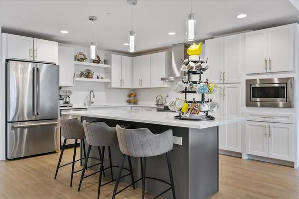a kitchen with stainless steel appliances granite countertop a sink a stove a refrigerator cabinets and chairs
