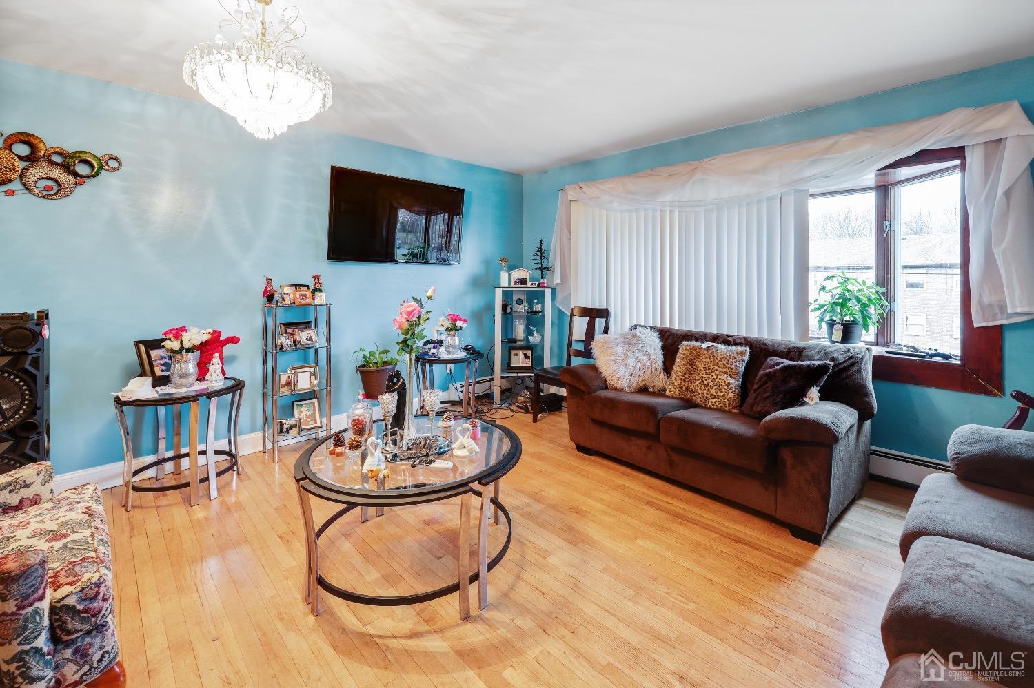 1096 Rudyard Drive Perth Amboy, NJ 08861 - Photo 2 of 10 a living room with furniture a flat screen tv and a floor to ceiling window